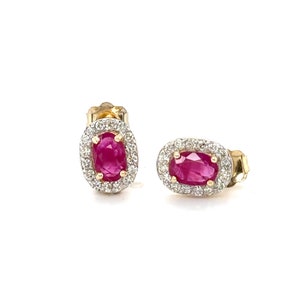 May include: A pair of gold earrings with oval ruby gemstones surrounded by a halo of smaller diamonds.