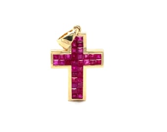 May include: A gold-colored cross pendant with a bail. The cross is filled with square, deep red gemstones. The pendant is set against a white background.