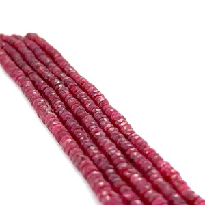 May include: A strand of ruby red faceted gemstone beads. The beads are small and round, and they are strung together on a clear thread.
