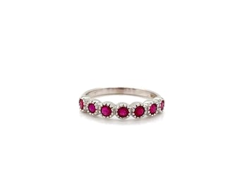 May include: A silver ring featuring a series of vibrant red gemstones. The gemstones are set in a row, creating a continuous band of color. The ring's design is simple yet elegant, with a polished finish that enhances the gemstones' brilliance.
