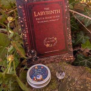 May include: An image of a red and gold "The Labyrinth" fact and magic guide card, a small tin with the text "It's only forever, not long at all," and two crystal balls. The items are displayed on a moss-covered tree stump.