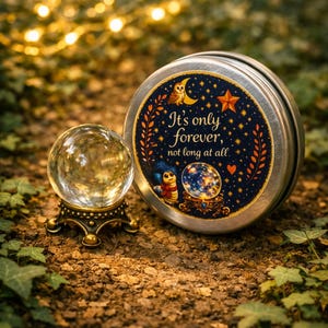 May include: A crystal ball on a decorative stand beside a round metal tin. The tin has a blue and gold label with an owl, star, and the text "It's only forever, not long at all."