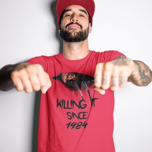 K&ouml;nnte beinhalten: Rotes T-Shirt mit einem schwarz-wei&szlig;en Motiv eines Vogels mit dem Text "KILLING IT SINCE 1984".