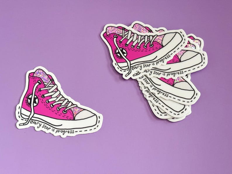 May include: Pink glitter high top sneakers with white laces and a black star on the side. The sneakers are on a sticker with the text "Every step is progress" repeated multiple times.