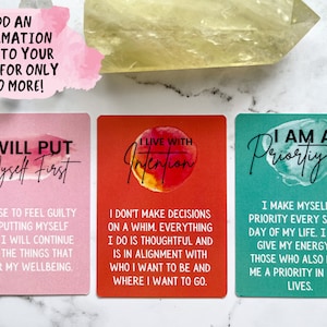 May include: Three affirmation cards with watercolor backgrounds. The first card is pink and says "I will put myself first". The second card is red and says "I live with intention". The third card is teal and says "I am a priority".