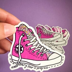 May include: Pink glitter high-top sneaker with white laces and a black star. The sneaker has the text "Never Quit" on the side and "every step is progress" on the bottom.