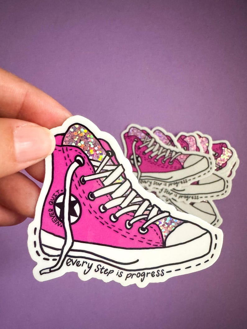 May include: Pink glitter high-top sneaker with white laces and a black star. The sneaker has the text "Never Quit" on the side and "every step is progress" on the bottom.