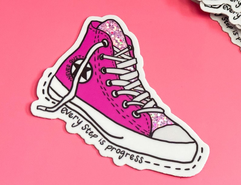 May include: Pink Converse-style sneaker with white laces and a black star. The sneaker has glitter on the side and the text "NEVER QUIT" on the side. The text "every step is progress" is written below the sneaker.