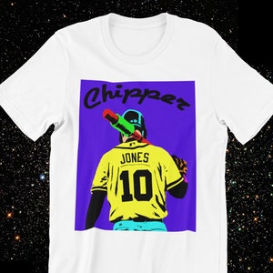 May include: White t-shirt with a colorful graphic of a baseball player holding a bat. The graphic has the text "Chipper" and "Jones 10" on it.