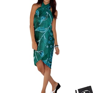 Könnte beinhalten: Ein türkisblauer und weißer Sarong mit floralem Muster. Der Sarong ist um die Taille gebunden und wird als Kleid getragen.