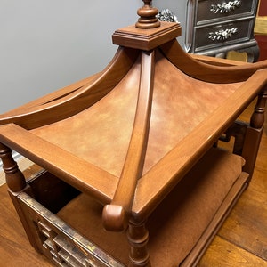 May include: A wooden dog bed with a pagoda-style roof. The bed is made of dark brown wood and has a brown fabric lining. The roof is topped with a finial.