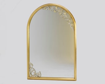May include: A gold arched mirror with ornate floral details around the frame.