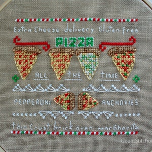May include: Cross-stitch embroidery on tan fabric, featuring pizza slices and text. The design includes the words "PIZZA," "Extra Cheese delivery gluten free," "ALL THE TIME," "PEPPERONI," "ANCHOVIES," and "thin crust brick oven margherita."