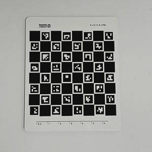 May include: A white rectangular calibration card with a black and white checkerboard pattern. The card has the text "PHOTON VISION" and measurements of 8 x 8 inches and 0.75 inches. The bottom edge has inch markings from 0 to 6.