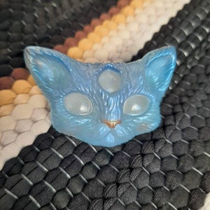 May include: A blue glass cat figurine with three eyes and a light blue iridescent finish.