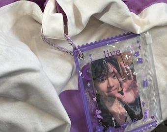 May include: A white and purple canvas tote bag with a large purple heart graphic. Attached is a clear plastic card holder with a purple scalloped border, featuring the text "i live" and "i love" and a photo of a person waving their hand.