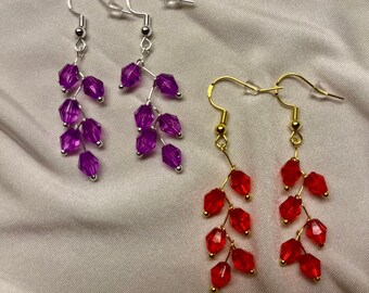 May include: Two pairs of dangle earrings with crystal beads. One pair has purple beads on silver hooks and the other pair has red beads on gold hooks.