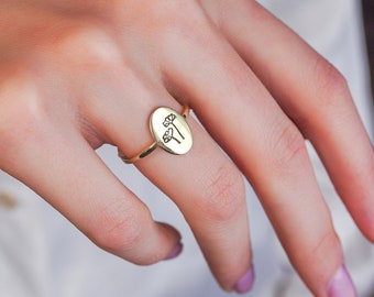 Puede incluir: Un anillo ovalado de oro con un delicado diseño floral grabado en la cara.