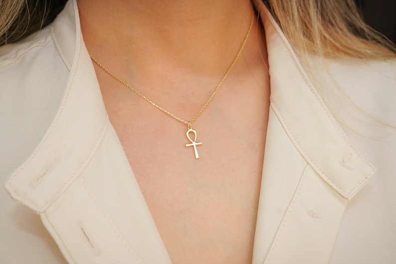 K&ouml;nnte beinhalten: Eine goldene Kettenkette mit einem Ankh-Anh&auml;nger.