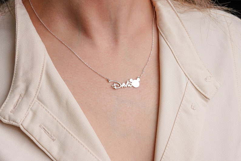 Puede incluir: Un collar de plata con el nombre "David" y un dije de cabeza de Mickey Mouse.