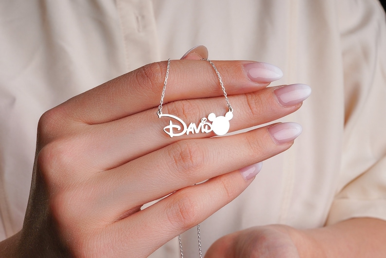Puede incluir: Collar de plata con el nombre "David" y un dije de cabeza de Mickey Mouse.