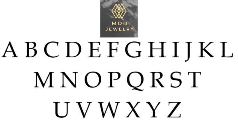 Op de afbeelding: Zwarte en witte alfabetletters A tot en met Z in een eenvoudig, sans-serif lettertype. De letters zijn gerangschikt in drie rijen. Het woord "MOD JEWELRY" staat boven de letters in een gouden, sans-serif lettertype.