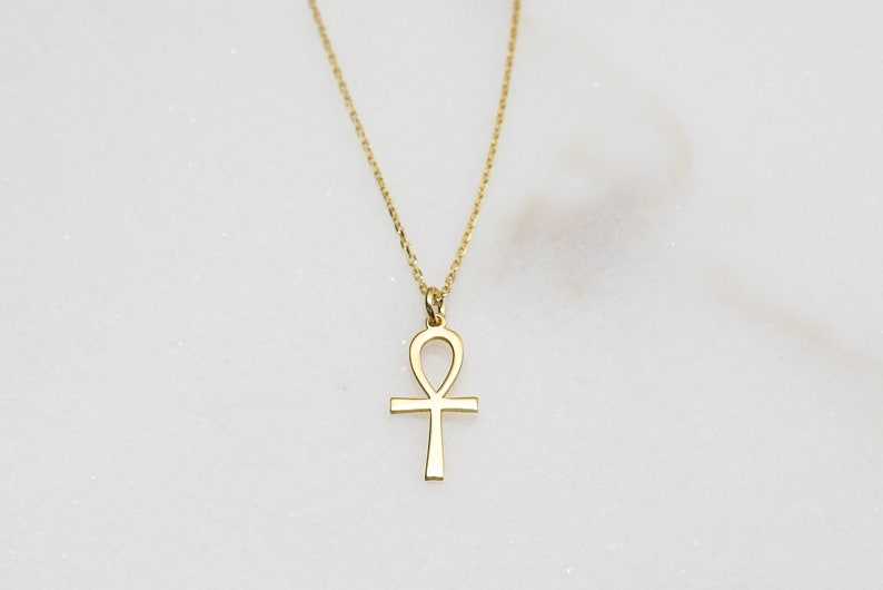 K&ouml;nnte beinhalten: Eine goldene Kettenkette mit einem goldenen Ankh-Anh&auml;nger.