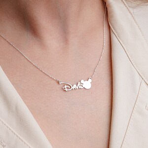 Puede incluir: Collar de plata con el nombre "David" en una fuente estilizada y un dije de cabeza de Mickey Mouse.