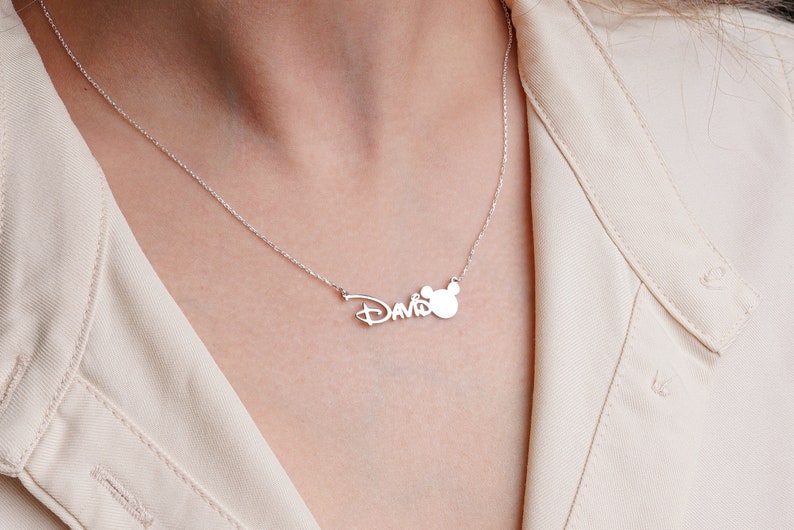 Puede incluir: Collar de plata con el nombre "David" en una fuente estilizada y un dije de cabeza de Mickey Mouse.