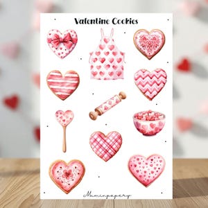 Könnte beinhalten: Aquarellillustration von Valentinstags-Keksen und Backutensilien. Das Bild zeigt herzförmige Kekse mit verschiedenen Designs, eine herzförmige Schürze und ein Nudelholz. Der Text "Valentine Cookies" steht oben.