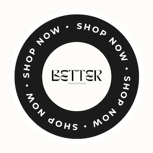 May include: A circular sticker with a black border and a white interior. The words "SHOP NOW" are written in white around the black border. The word "BETTER" is in the center, with "CREATOR STUDIOS" below it.