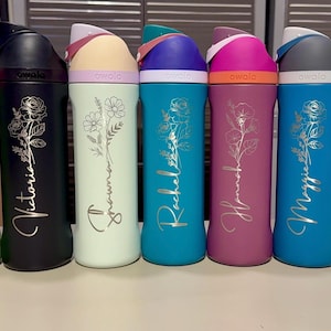 Puede incluir: Una colecci&oacute;n de botellas de agua aisladas en varios colores, incluyendo verde, negro, menta, turquesa, magenta, azul y blanco. Cada botella presenta un dise&ntilde;o floral y un nombre en fuente cursiva. Las botellas tienen una tapa abatible.