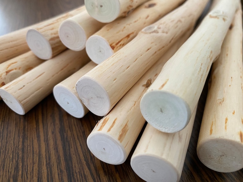 Pu&ograve; includere: Una collezione di tasselli di legno di colore chiaro, ciascuno con un aspetto naturale e non rifinito. Le estremit&agrave; sono tagliate in modo pulito, rivelando la venatura del legno. I tasselli sono disposti in modo leggermente sovrapposto.