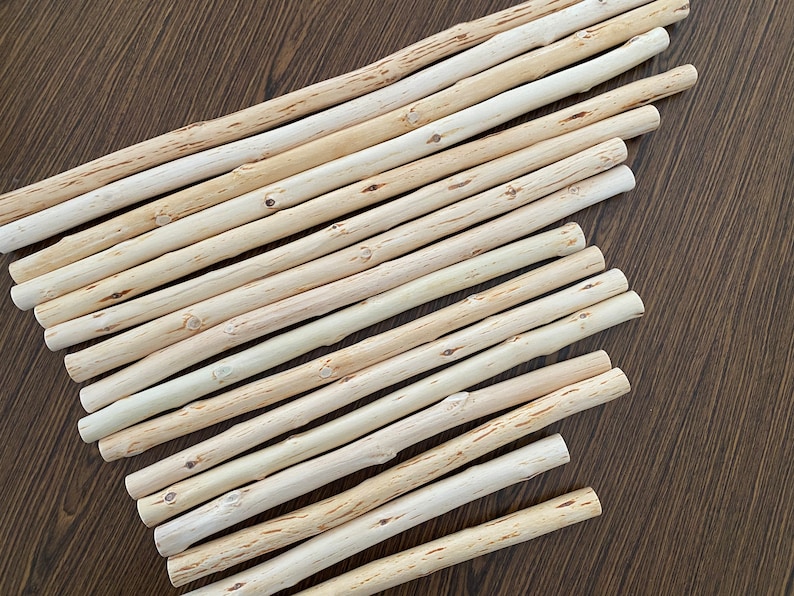 Pu&ograve; includere: Una collezione di tasselli di legno di colore chiaro, disposti diagonalmente su una superficie di legno marrone scuro. I tasselli hanno un aspetto naturale, non rifinito, con nodi visibili e variazioni di colore.
