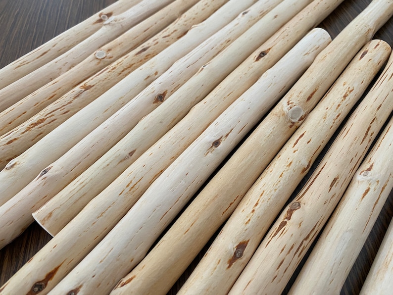 Pu&ograve; includere: Una collezione di tasselli in legno naturale di colore chiaro disposti diagonalmente. I tasselli hanno una forma cilindrica liscia con nodi visibili e sottili variazioni di colore, che vanno dal crema al marrone chiaro. Ideale per progetti di artigianato.