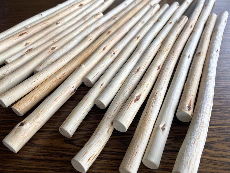Pu&ograve; includere: Una collezione di tasselli di legno di colore chiaro, che variano in tonalit&agrave; beige e marrone chiaro, sono disposti diagonalmente su una superficie di legno scuro. I tasselli hanno un aspetto naturale, non rifinito, con venature e nodi del legno visibili.