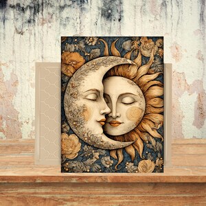 May include: A decorative print featuring a celestial design of a crescent moon and a sun with closed eyes, kissing. The artwork is set against a dark blue floral background with gold and cream accents. The print is displayed on a wooden surface.