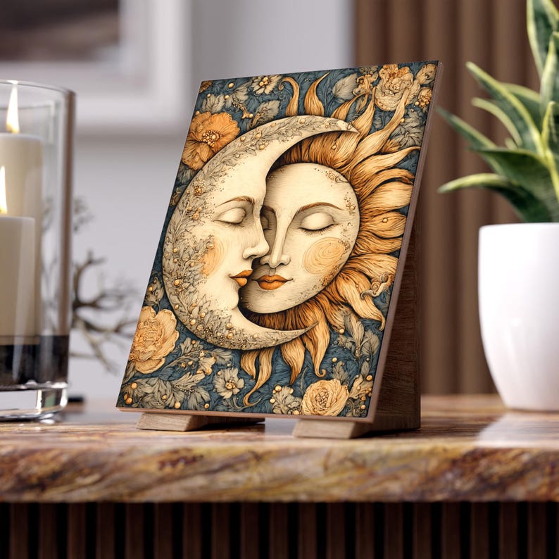 May include: A wooden decorative plaque featuring a celestial design of the sun and moon embracing. The artwork has a vintage style with floral accents and a blue background. The plaque is supported by a wooden stand and is displayed on a marble surface.