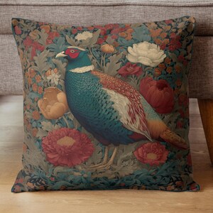 May include: Square decorative pillow featuring a detailed illustration of a pheasant amidst a floral pattern. The bird has blue, red, and brown plumage, surrounded by red, white, and orange flowers on a dark background.