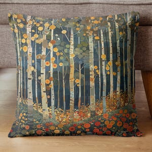 May include: Decorative square pillow featuring a forest scene with tall, white birch trees and a path. The pillow has a dark blue background with orange and yellow flowers at the base of the trees. The pillow is on a gray couch.