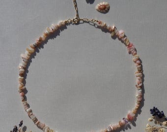 May include: A delicate pink opal stone necklace with a gold clasp. The necklace is made of small, irregular shaped stones and is perfect for layering.