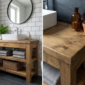 K&ouml;nnte beinhalten: Ein rustikaler Badezimmerschrank aus Holz mit einem rechteckigen wei&szlig;en Keramik-Aufsatzwaschbecken, zwei offenen Ablagef&auml;chern, einem geflochtenen Korb und grauen Handt&uuml;chern. Der Schrank steht vor einer wei&szlig;en Fliesenwand mit einem runden schwarzen Spiegel.