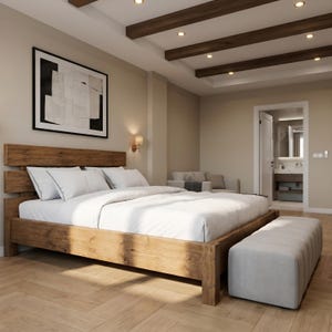 May include: A bedroom with a wooden bed frame, white bedding, and a light grey bench. The room has a neutral colour scheme with wooden beams on the ceiling and a framed abstract artwork on the wall. The room has a door leading to a bathroom.