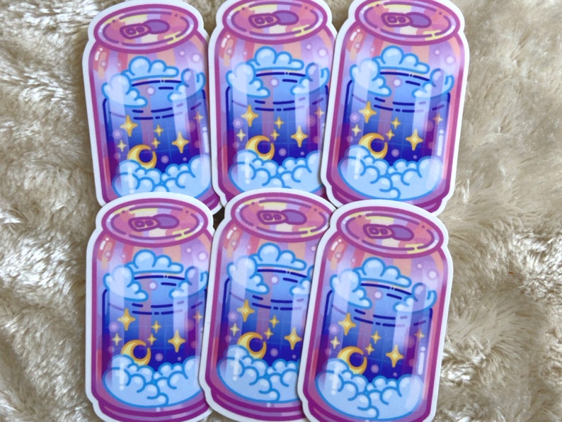 May include: Six colorful stickers of a can filled with a blue and purple liquid with white clouds and stars. The can has a pink and yellow striped design.