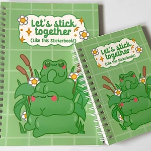 Può includere: Due quaderni a spirale con un design a forma di rana verde. I quaderni hanno il testo "Let's stick together (Like this Stickerbook!)". Lo sfondo è un motivo a griglia verde chiaro. L'illustrazione della rana è verde con guance rosa.