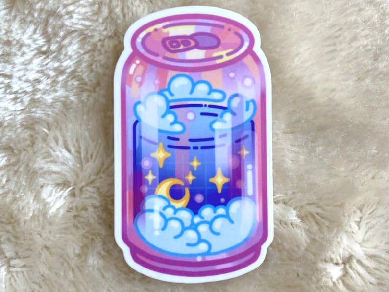 May include: A pink and blue can with a starry night sky inside. The can has a white lid and a white rim. There are clouds and a crescent moon in the sky.