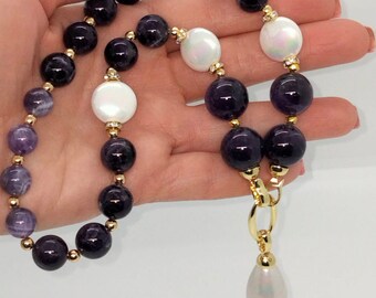 May include: A purple amethyst and white pearl necklace with a gold clasp and a single pearl pendant.