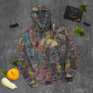 May include: A gray hoodie with a colorful abstract print featuring graffiti-style designs. The hoodie has a drawstring hood and a kangaroo pocket.