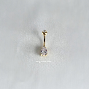 May include: Gold belly button ring with a clear pear-shaped gem.