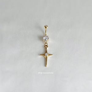 May include: Gold belly button ring with a clear crystal star charm and a smaller clear crystal on the top of the ring.